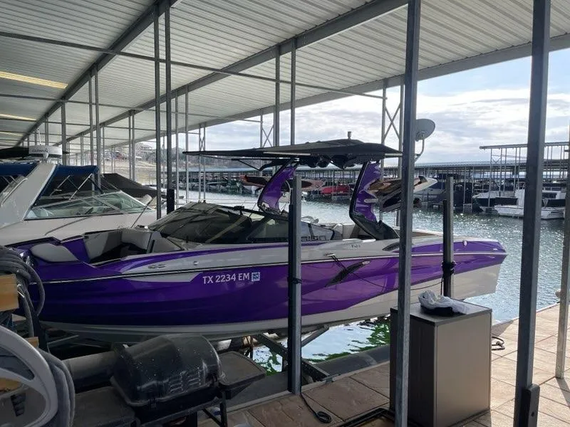 Slide: The Image of 2019 Centurion Fi25 boat in a marina, featuring a vibrant purple exterior. - 2
