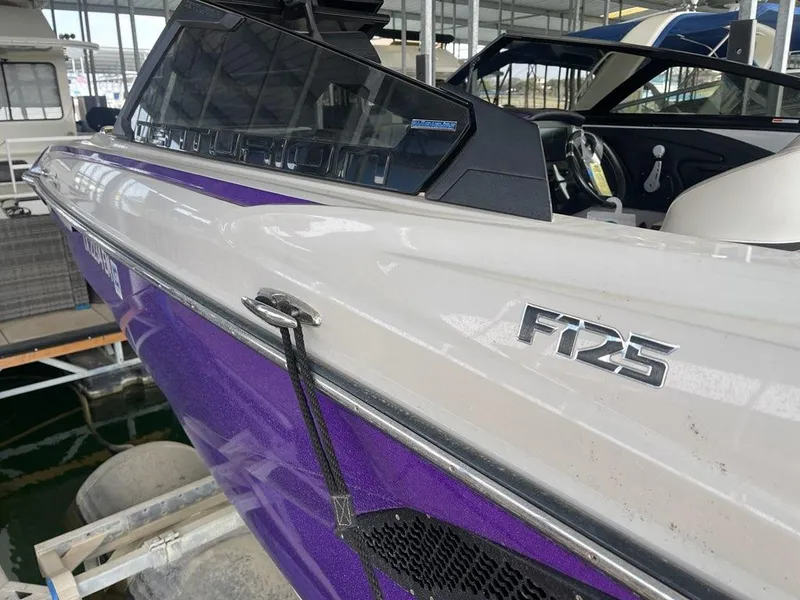 Slide: The Image of 2019 Centurion Fi25 boat with purple and white exterior, docked in a marina. - 6