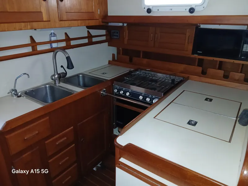Slide: The Image of 1992 Valiant 40 yacht kitchen with wooden cabinetry, dual sinks, stove, and microwave. - 16