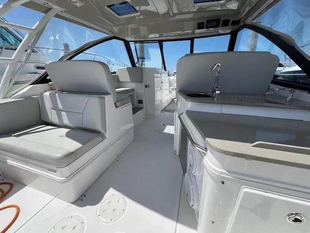 Slide: The Image of 2019 Everglades 340 Dual Console interior with seating and kitchenette, featuring modern design. - 13