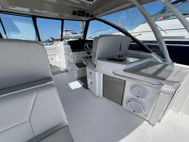 Slide: The Image of 2019 Everglades 340 Dual Console interior with seating, helm, and kitchenette. - 14