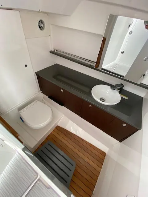 Slide: The Image of 2019 Everglades 340 Dual Console boat bathroom with sink, toilet, and wooden floor. - 19