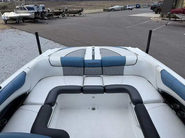 Slide: The Image of 2013 MasterCraft X45 boat interior with blue and white seating, parked near other boats. - 13