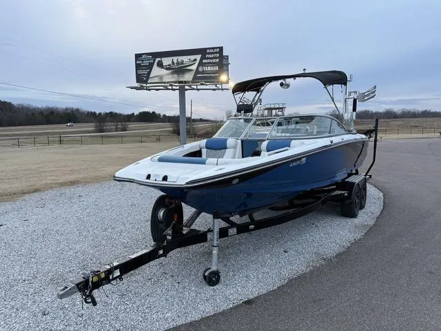 Slide: The Image of 2013 MasterCraft X45 boat on trailer, parked on gravel near a billboard. - 4
