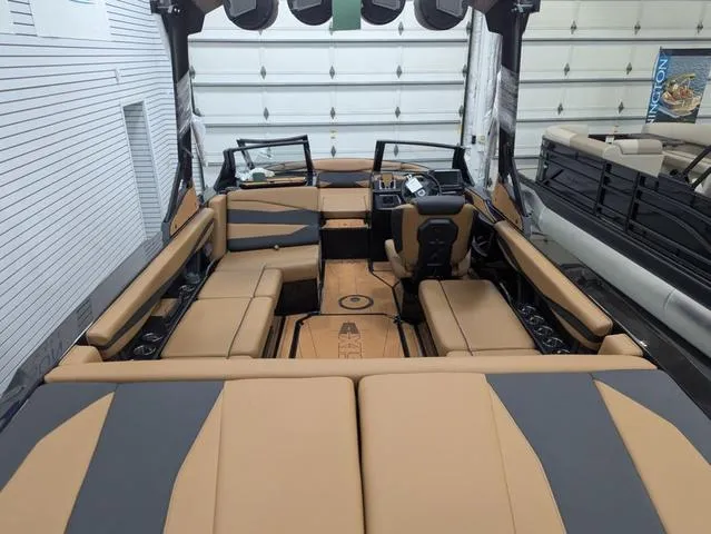 Slide: The Image of 2025 Axis Wake Research A225 boat interior with tan and gray seating in a garage. - 4