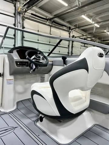Slide: The Image of 2024 Chaparral 21 SSi boat interior with steering wheel and captain's chair in a garage. - 8