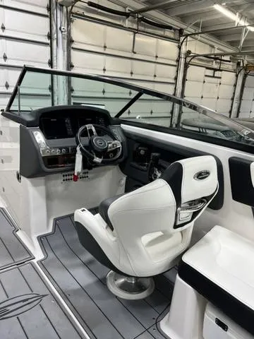 Slide: The Image of 2022 Chaparral 28 Surf boat interior with modern helm and seating in a garage. - 12