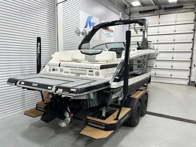 Slide: The Image of 2022 Chaparral 28 Surf boat in showroom, featuring sleek design and dual-axle trailer. - 6