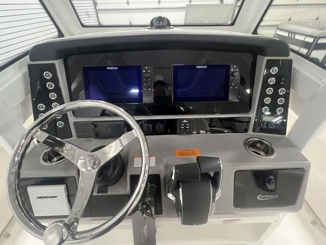 Slide: The Image of 2024 Robalo R250 boat dashboard with dual Simrad displays and Mercury controls. - 19