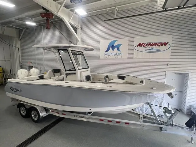Slide: The Image of 2024 Robalo R250 boat on trailer in showroom, Munson Marine banners visible. - 2