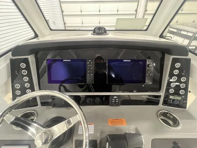 Slide: The Image of 2024 Robalo R250 boat dashboard with dual Simrad displays and steering wheel. - 20