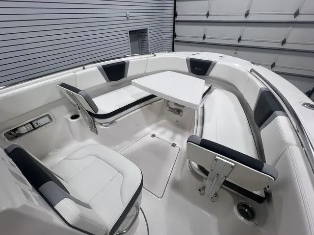 Slide: The Image of 2024 Robalo R250 boat interior with white seating and table in a garage setting. - 27