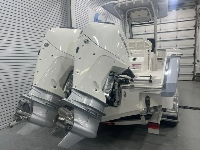 Slide: The Image of 2024 Robalo R250 boat with dual outboard engines in a showroom. - 3