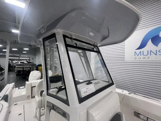 Slide: The Image of 2024 Robalo R250 boat interior, showcasing helm and seating in showroom. - 32