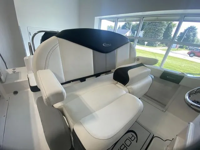 Slide: The Image of 2024 Robalo R222EX boat interior with white seating and armrests, near large windows. - 10