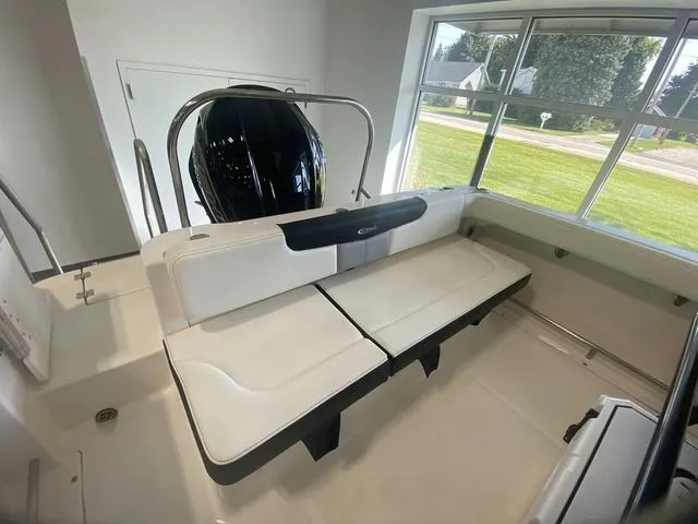 Slide: The Image of 2024 Robalo R222EX boat interior with white seating and outboard motor, near large window. - 7