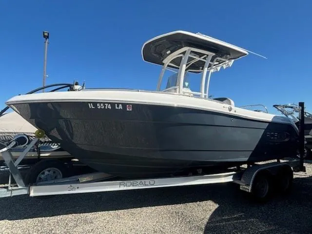 Slide: The Image of 2021 Robalo R222 boat on trailer under clear blue sky. - 8