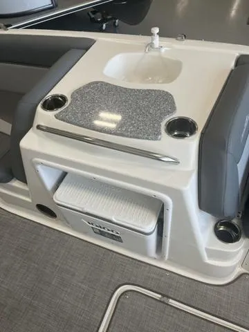 Slide: The Image of 2024 NauticStar 203 SC boat interior with sink, storage, and cup holders. - 7
