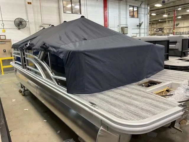 Slide: The Image of 2025 Bennington 22 SSB pontoon boat with cover in a warehouse setting. - 13