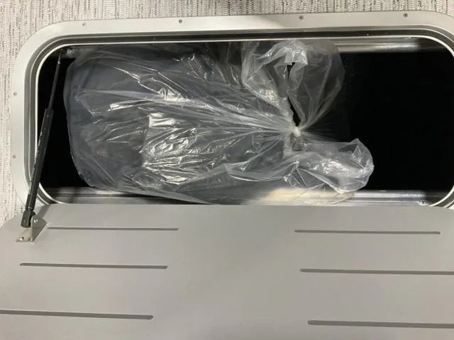 Slide: The Image of Storage compartment in a 2025 Bennington 23 SSB boat with a plastic-covered item inside. - 12