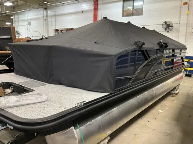 Slide: The Image of 2025 Bennington 23 SSB pontoon boat with cover in a warehouse setting. - 16