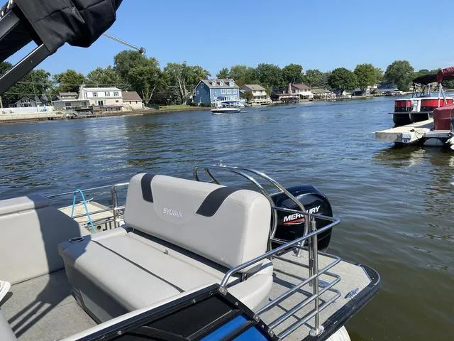 Slide: The Image of 2021 Sylvan L-3 DLZ pontoon boat on a scenic lake with houses in the background. - 11