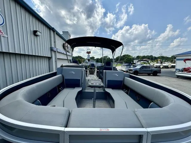 Slide: The Image of 2022 Bennington 25 LTSB pontoon boat with spacious seating and canopy, parked outdoors. - 27