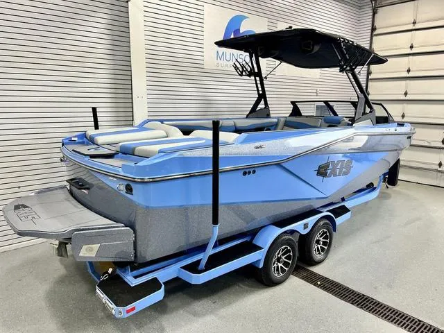 Slide: The Image of 2024 Axis Wake Research T250 boat in showroom, blue and gray design, on trailer. - 4
