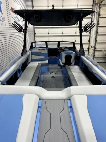 Slide: The Image of 2024 Axis Wake Research T250 boat interior with blue and gray seating in a showroom. - 6