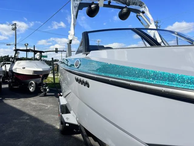 Slide: The Image of 2024 Axis Wake Research T250 boat with sparkling teal accent, parked outdoors. - 2