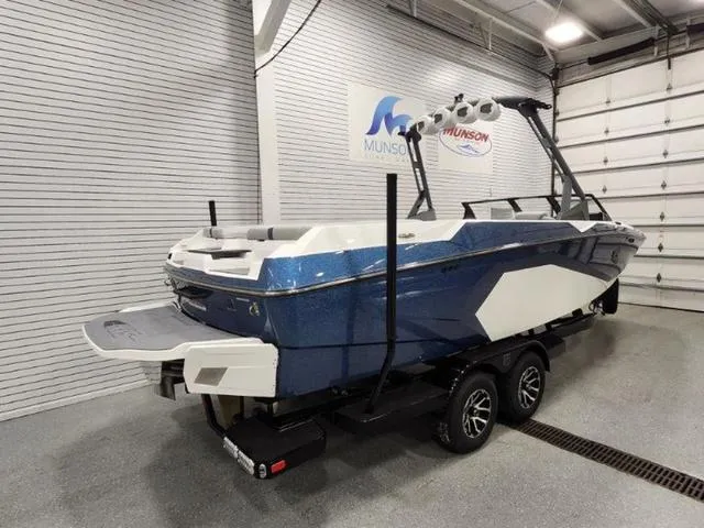 Slide: The Image of 2024 Axis Wake Research A245 boat in showroom, blue and white design, on trailer. - 3