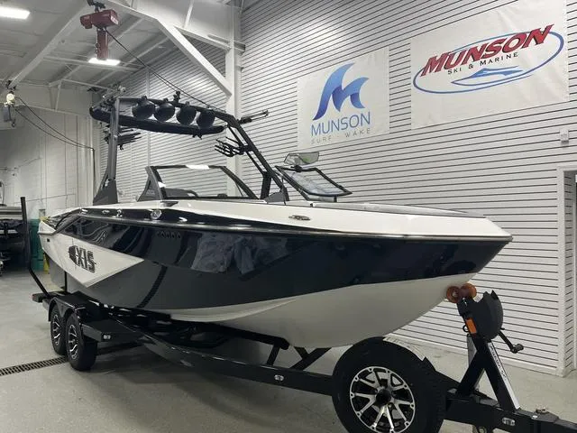 Slide: The Image of 2024 Axis Wake Research T235 boat in showroom, black and white design, on trailer. - 2