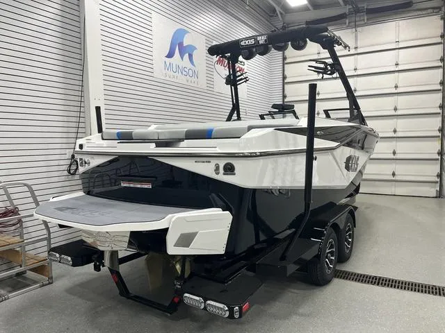 Slide: The Image of 2024 Axis Wake Research T235 boat in showroom, black and white design, on trailer. - 3
