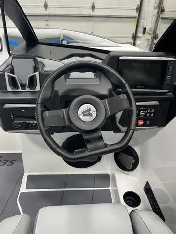 Slide: The Image of 2024 Axis Wake Research T235 boat dashboard with steering wheel and control panel. - 8