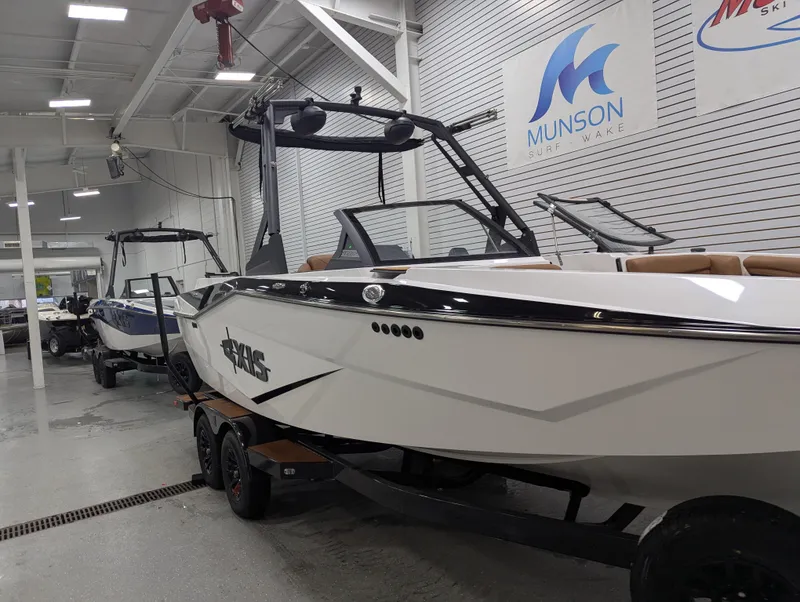 Slide: The Image of 2025 Axis T220 boat in showroom, sleek design, Munson Ski & Marine signage. - 2
