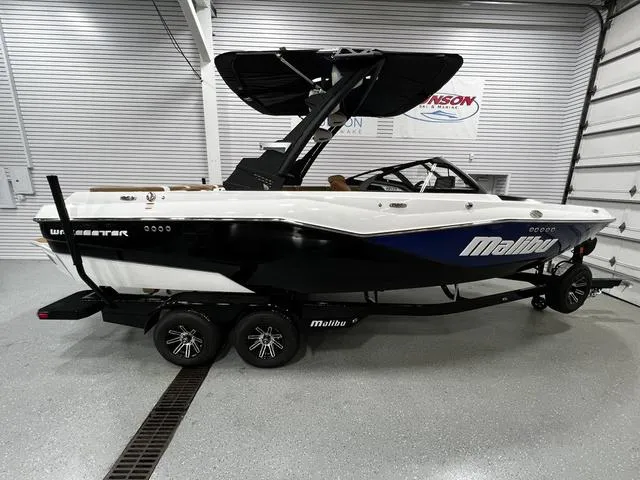 Slide: The Image of 2024 Malibu 22 LSV boat in showroom, black and white design, on trailer. - 1