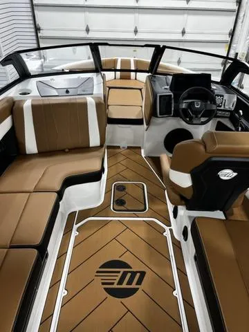 Slide: The Image of 2024 Malibu 22 LSV boat interior with brown and white seating, modern dashboard, and stylish flooring. - 10