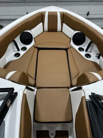 Slide: The Image of 2024 Malibu 22 LSV boat interior with tan and white seating, cup holders, and speakers. - 11