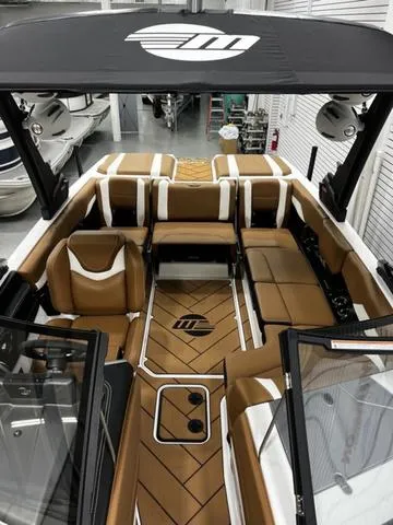 Slide: The Image of 2024 Malibu 22 LSV boat interior with tan and white seating, black canopy, and sleek design. - 12