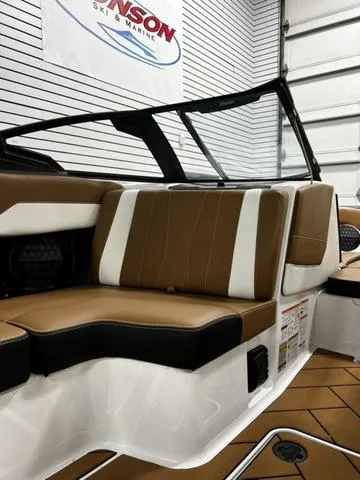 Slide: The Image of 2024 Malibu 22 LSV boat interior with brown and white seating in showroom. - 18