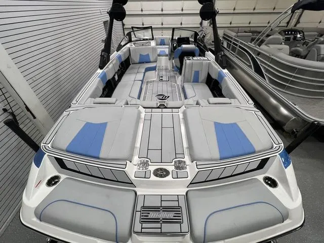 Slide: The Image of 2024 Malibu 24 MXZ boat with sleek interior design and blue accents in a showroom. - 5