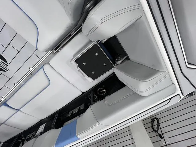 Slide: The Image of 2024 Malibu 24 MXZ boat interior with sleek white and blue seating design. - 7