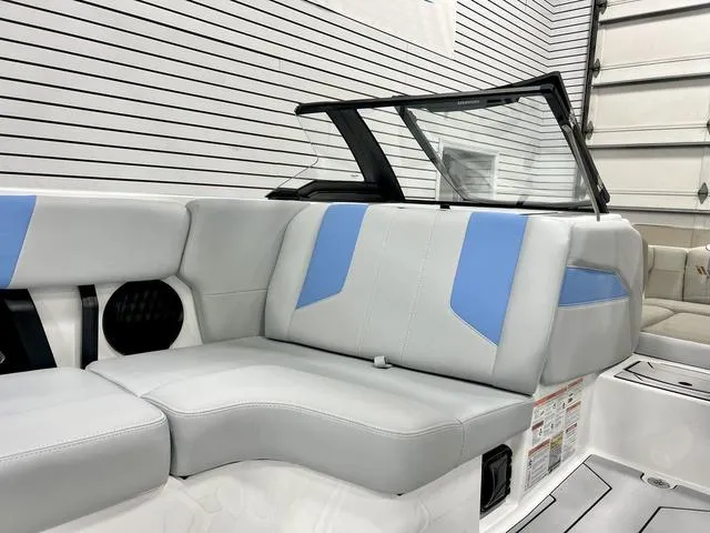 Slide: The Image of 2024 Malibu 21 LX boat interior with blue and gray seating in a showroom. - 11