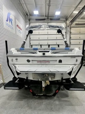 Slide: The Image of 2024 Malibu 21 LX boat in a showroom, rear view with visible propeller and swim platform. - 4