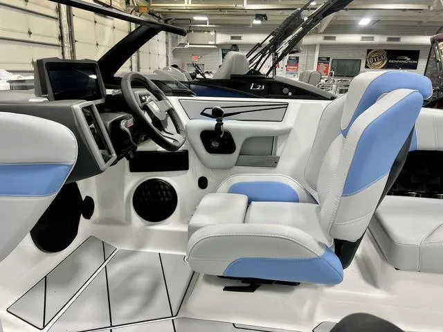 Slide: The Image of 2024 Malibu 21 LX boat interior with blue and white seating, modern dashboard, and steering wheel. - 9