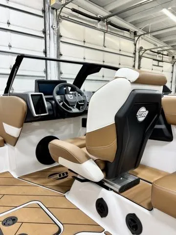 Slide: The Image of 2024 Malibu 22 LSV boat interior with tan and white seating in a garage setting. - 10