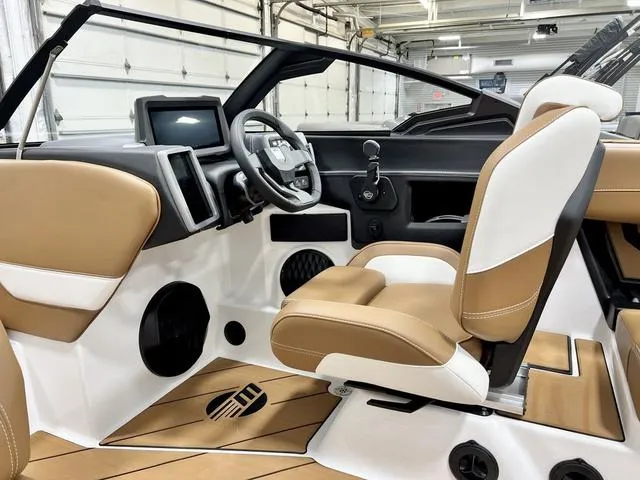 Slide: The Image of 2024 Malibu 22 LSV boat interior with tan and white seating, modern dashboard, and steering wheel. - 11