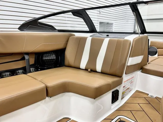 Slide: The Image of 2024 Malibu 22 LSV boat interior with tan and white seating, modern design. - 14