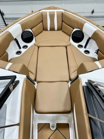 Slide: The Image of 2024 Malibu 22 LSV boat interior with tan and white cushioned seating. - 8