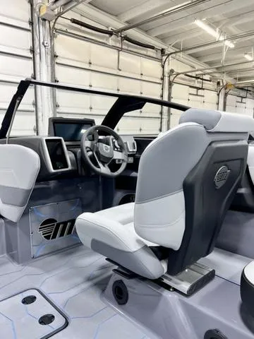 Slide: The Image of 2024 Malibu 23 MXZ boat interior with modern seating and dashboard in a garage setting. - 10